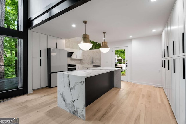 5020 Vallo Vista Ct, Atlanta, GA 30342 - kitchen featuring freestanding refrigerator, range, visible vents, a kitchen island, and white cabinets