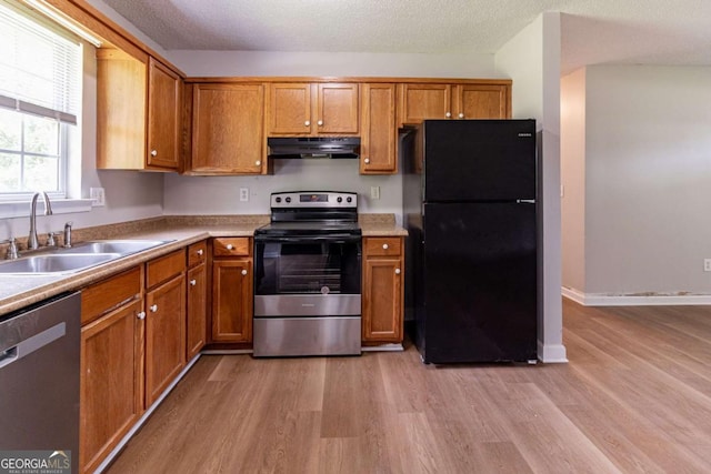 67 Jennifer Ln, Rydal, GA 30171 - kitchen with appliances with stainless steel finishes, under cabinet range hood, light wood-style flooring, brown cabinets, and a textured ceiling