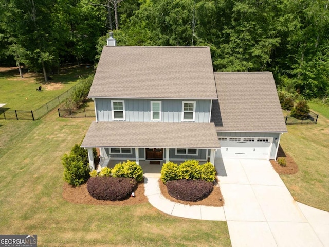 colonial-style house featuring board and batten siding, covered porch, driveway, fence, and a front lawn
