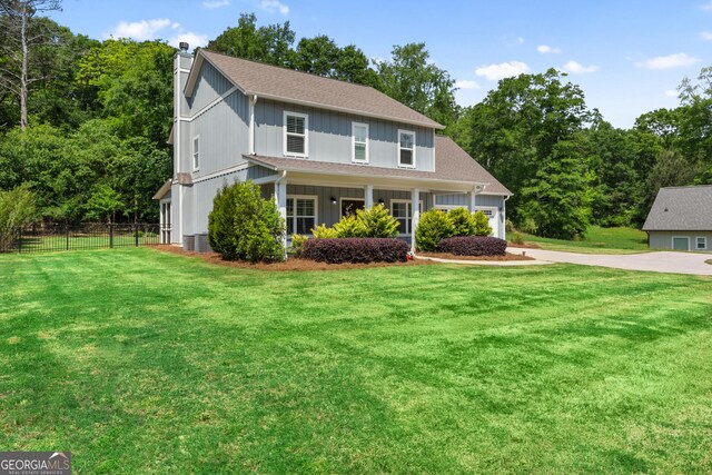 traditional-style house featuring fence, a front yard, a chimney, an attached garage, and driveway