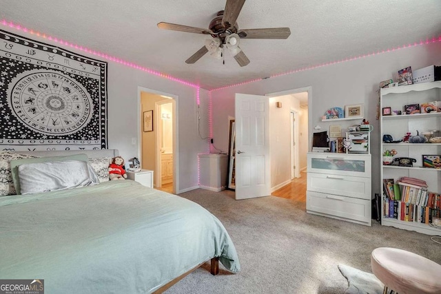 bedroom with light carpet, ensuite bath, a textured ceiling, a ceiling fan, and baseboards