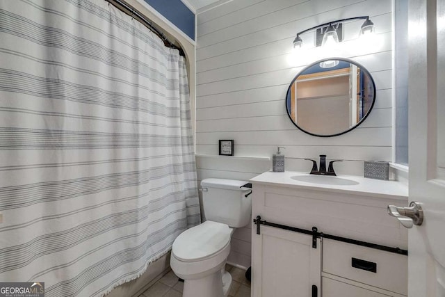full bath featuring toilet, tile patterned floors, wood walls, and vanity