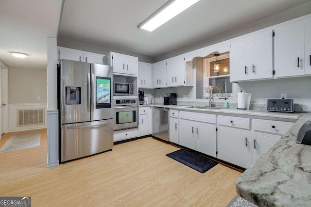 kitchen with visible vents, a sink, white cabinetry, and stainless steel appliances