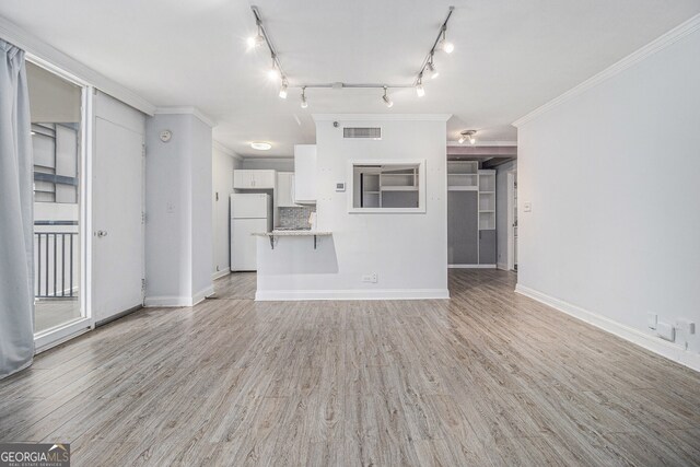 620 Peachtree St NE Unit 601, Atlanta, GA 30308 - unfurnished living room with crown molding, baseboards, visible vents, and light wood-type flooring