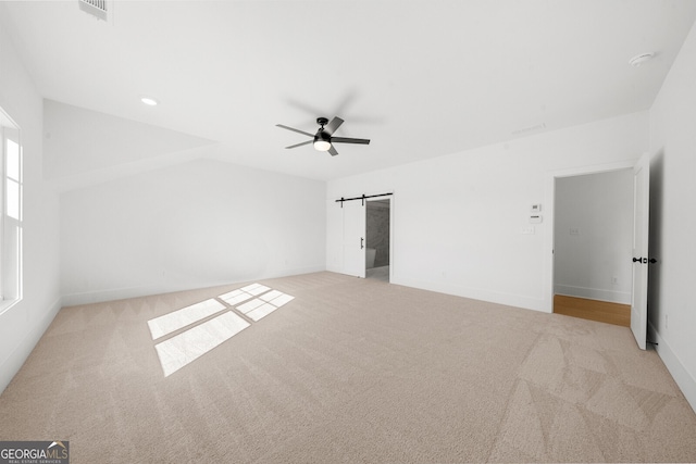 unfurnished bedroom with visible vents, a barn door, carpet, and baseboards