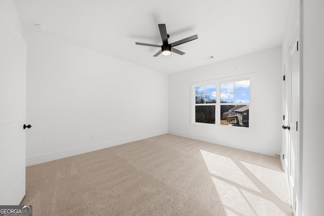 carpeted empty room with visible vents, baseboards, and ceiling fan