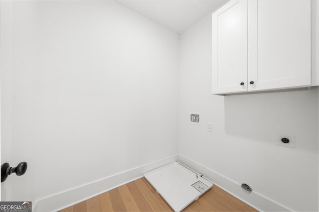 washroom with baseboards, electric dryer hookup, cabinet space, and wood finished floors