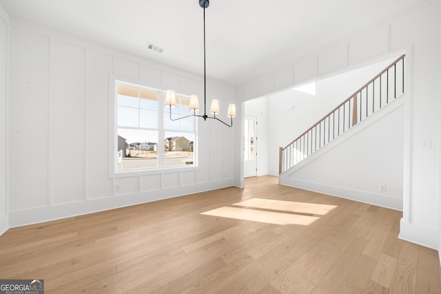 unfurnished dining area featuring an inviting chandelier, visible vents, and a decorative wall