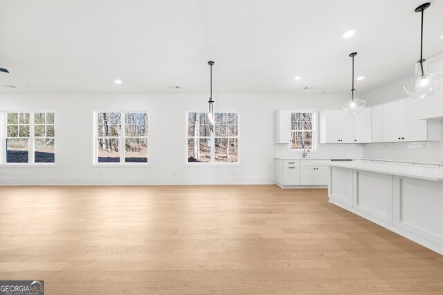 kitchen with light wood-style floors, a sink, a healthy amount of sunlight, and light countertops
