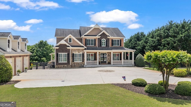 view of front facade with stone siding, board and batten siding, a porch, a front yard, and curved driveway