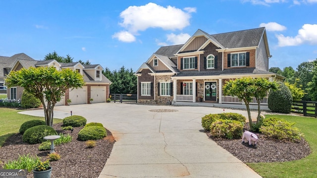 craftsman-style house with board and batten siding, a garage, curved driveway, fence, and stone siding