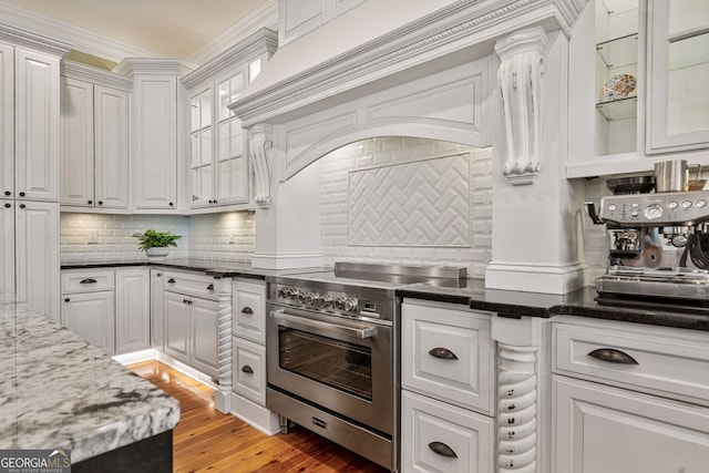 kitchen with high end stove, white cabinetry, and tasteful backsplash