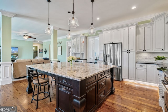 kitchen featuring white cabinets, a kitchen bar, stainless steel refrigerator with ice dispenser, and ceiling fan