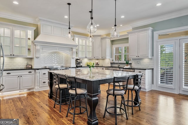 kitchen featuring wood finished floors, a kitchen island, a breakfast bar, and hanging light fixtures