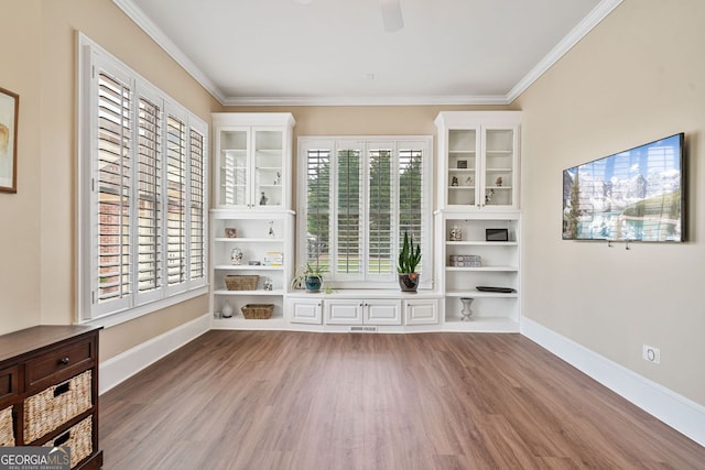 unfurnished room featuring crown molding, a ceiling fan, baseboards, wood finished floors, and visible vents