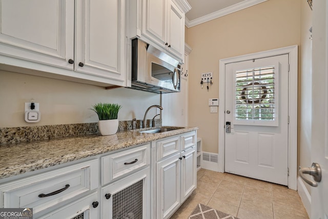 doorway to outside with a sink, light tile patterned floors, ornamental molding, and baseboards