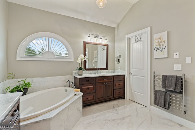 bathroom with marble finish floor, vaulted ceiling, a garden tub, and vanity