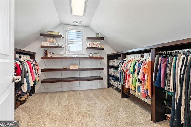 spacious closet with carpet flooring, visible vents, and lofted ceiling