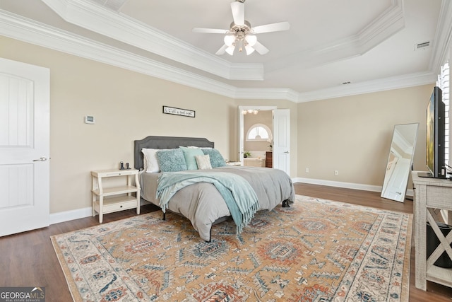 bedroom featuring crown molding, a raised ceiling, wood finished floors, and visible vents