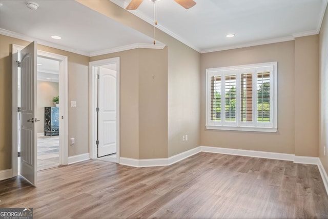 empty room with crown molding, a ceiling fan, baseboards, and wood finished floors