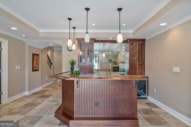 bar with baseboards, arched walkways, wet bar, and crown molding