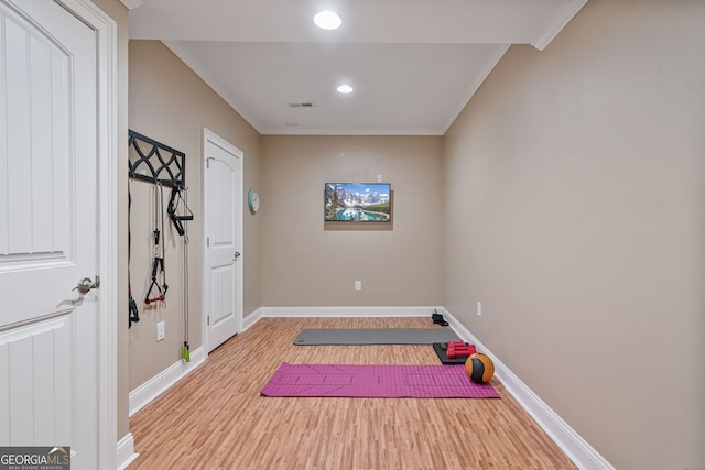 exercise area featuring crown molding, light wood-style flooring, recessed lighting, baseboards, and visible vents