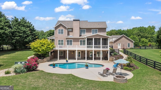 back of property with a fenced backyard, a chimney, a sunroom, a patio area, and an outdoor fire pit