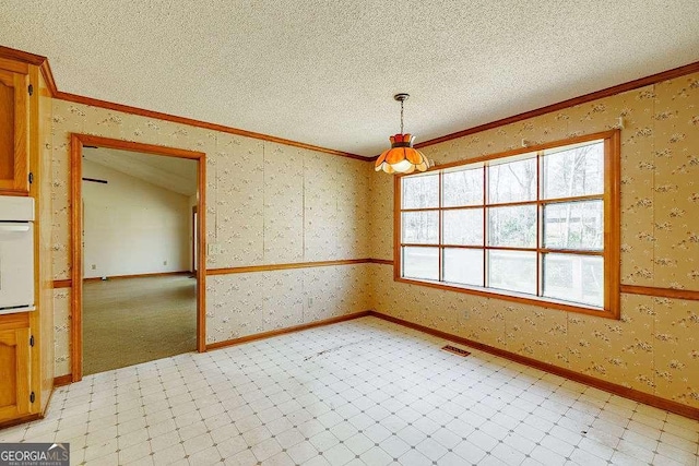 unfurnished dining area with visible vents, ornamental molding, baseboards, wallpapered walls, and a textured ceiling