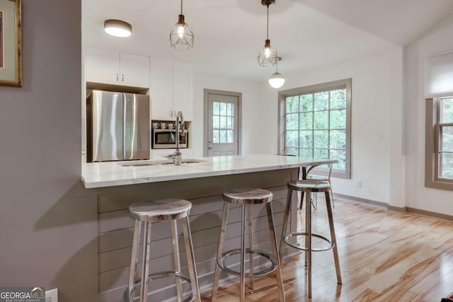 kitchen with a healthy amount of sunlight, appliances with stainless steel finishes, white cabinets, and a breakfast bar area