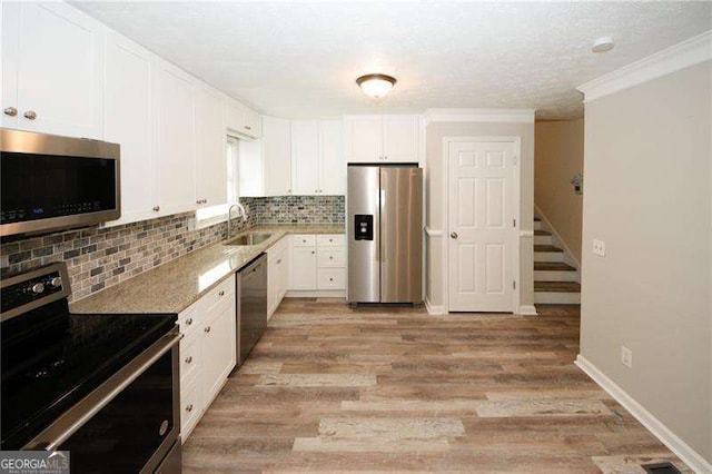 1616 W Kellogg Cir, Douglasville, GA 30134 - kitchen featuring backsplash, appliances with stainless steel finishes, a sink, white cabinets, and light wood-style flooring