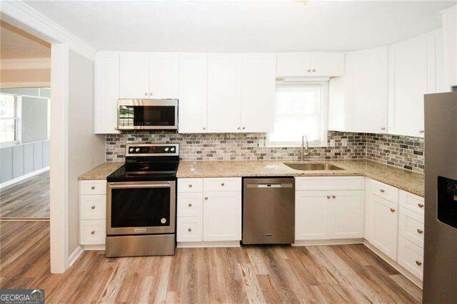 1616 W Kellogg Cir, Douglasville, GA 30134 - kitchen with a sink, light wood finished floors, white cabinetry, and stainless steel appliances
