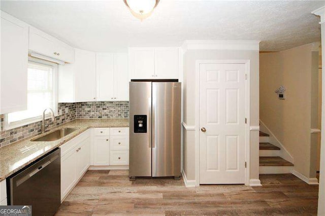 1616 W Kellogg Cir, Douglasville, GA 30134 - kitchen featuring decorative backsplash, light wood-type flooring, white cabinetry, a sink, and appliances with stainless steel finishes