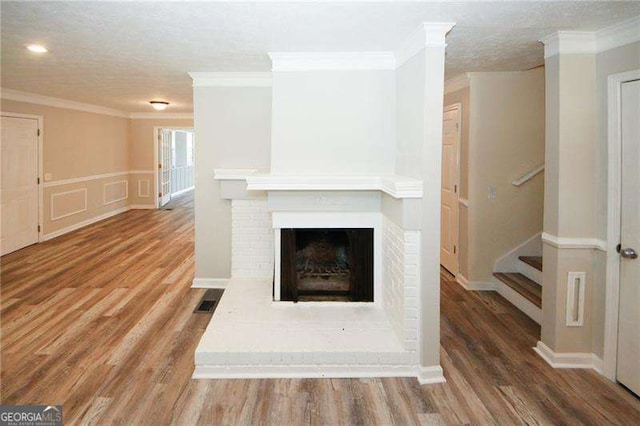 1616 W Kellogg Cir, Douglasville, GA 30134 - unfurnished living room with crown molding, stairway, a brick fireplace, and wood finished floors