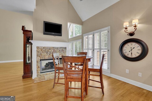 4810 Duncans Lake Dr, Buford, GA 30519 - dining room featuring light wood-style floors, high vaulted ceiling, baseboards, and a fireplace