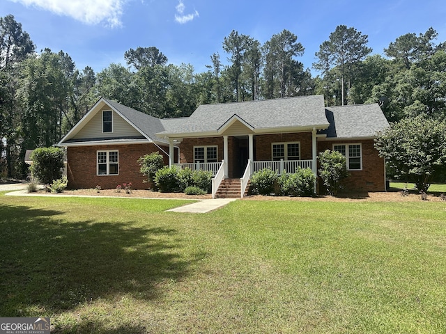 view of front facade with covered porch, brick siding, a shingled roof, and a front yard