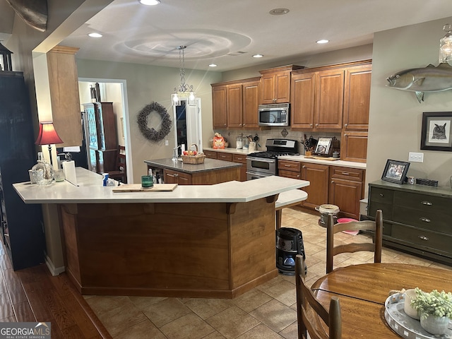 kitchen featuring appliances with stainless steel finishes, brown cabinetry, a center island, recessed lighting, and tasteful backsplash