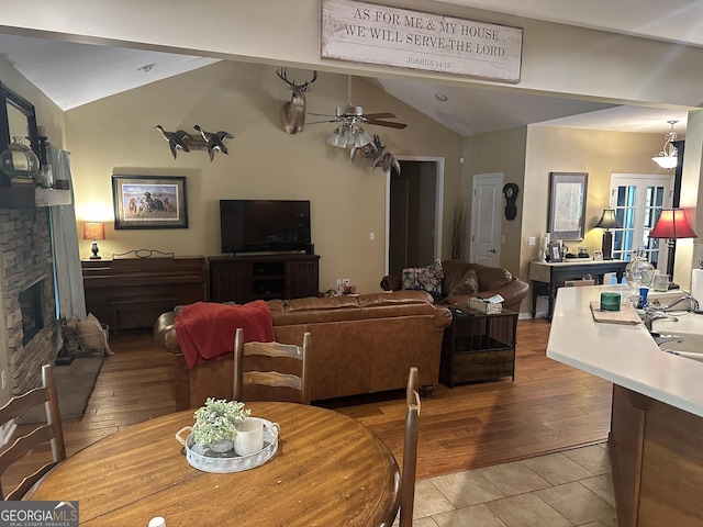 living area with light wood finished floors, ceiling fan, lofted ceiling, and a fireplace