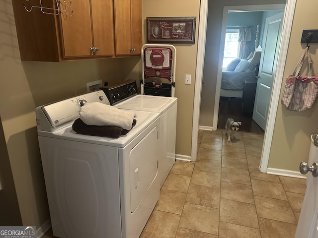 clothes washing area featuring independent washer and dryer, baseboards, and cabinet space