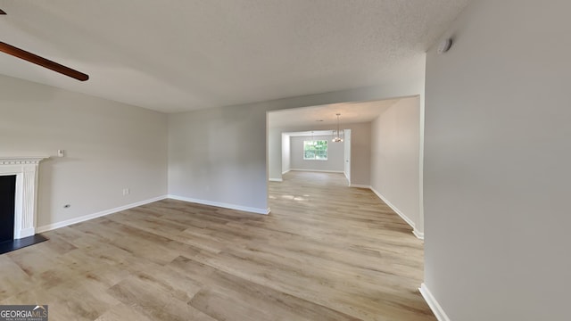 5326 Nader Pl, Stone Mountain, GA 30088 - unfurnished living room featuring a ceiling fan, baseboards, a fireplace with raised hearth, and light wood-style floors