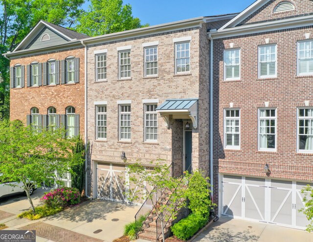 townhome / multi-family property featuring a garage, driveway, and brick siding