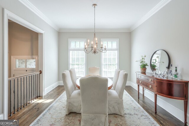 dining space featuring baseboards, ornamental molding, wood finished floors, and a notable chandelier