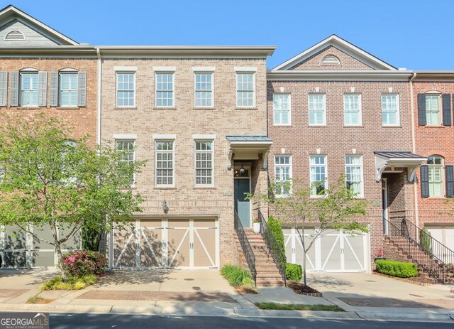 townhome / multi-family property with stairs, an attached garage, and driveway