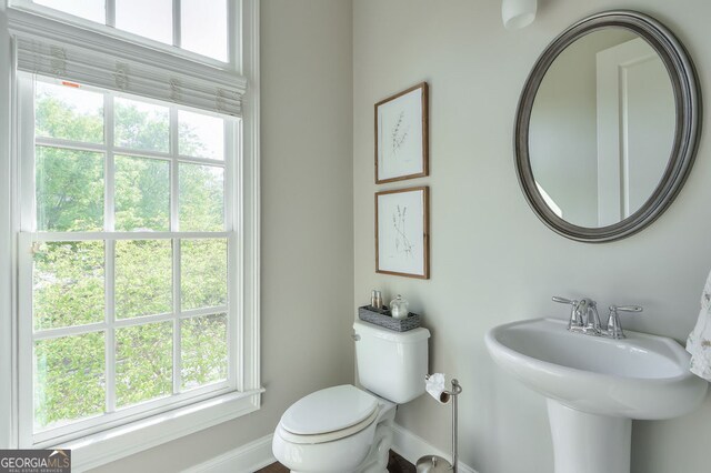 half bath with plenty of natural light, baseboards, and toilet