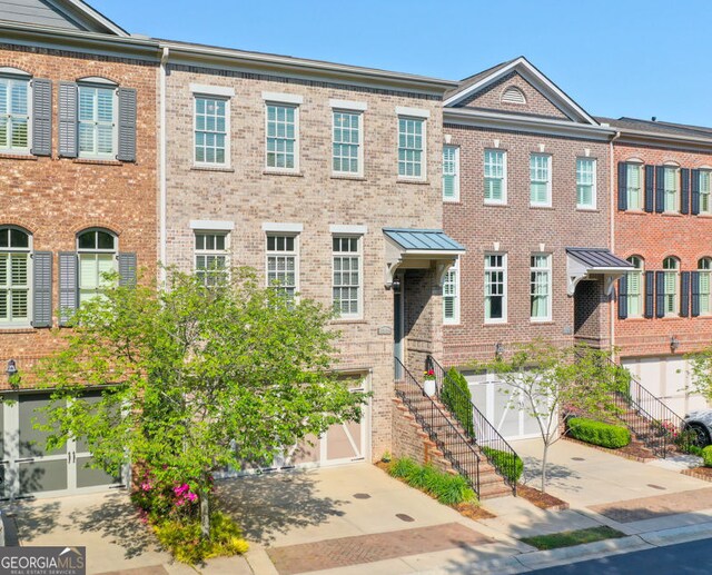 townhome / multi-family property with stairs, an attached garage, concrete driveway, and brick siding