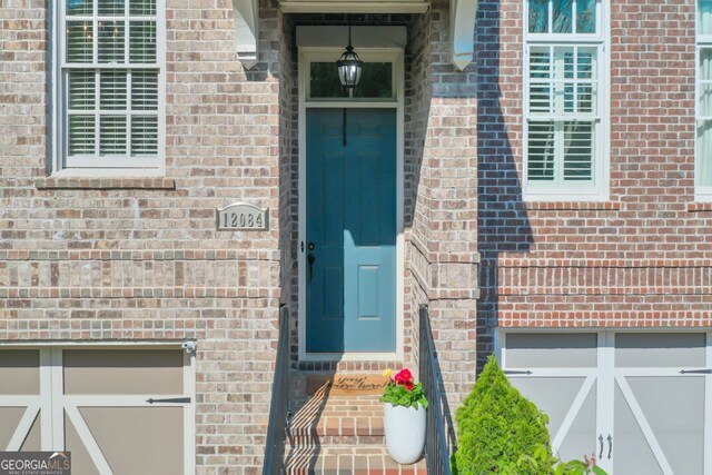 entrance to property featuring brick siding and a garage