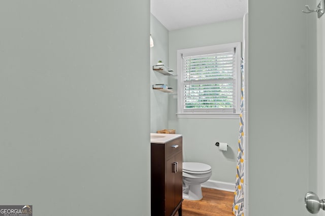 full bath featuring toilet, wood finished floors, a shower with shower curtain, baseboards, and vanity