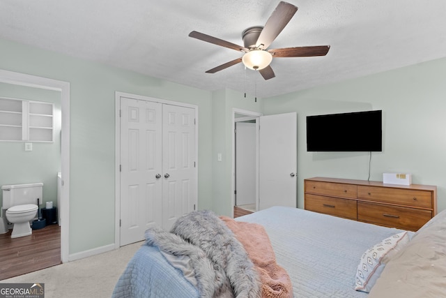carpeted bedroom featuring a closet, connected bathroom, baseboards, and ceiling fan