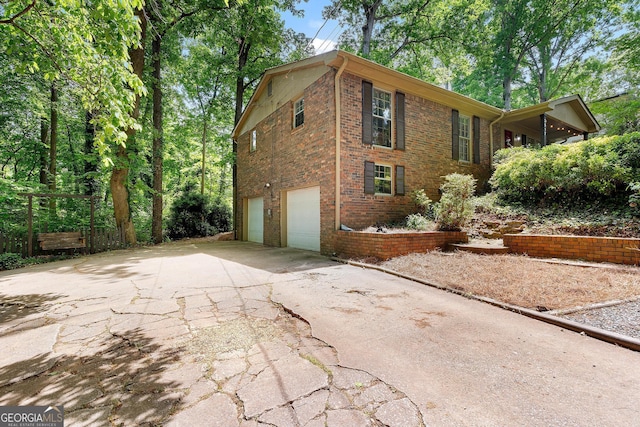 view of property exterior with an attached garage, brick siding, and driveway