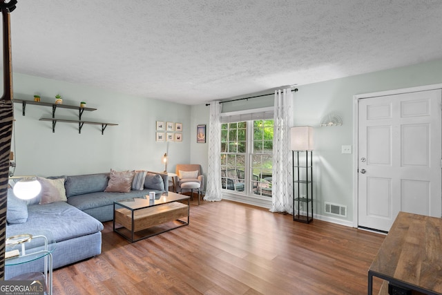 living area featuring a textured ceiling, visible vents, and wood finished floors