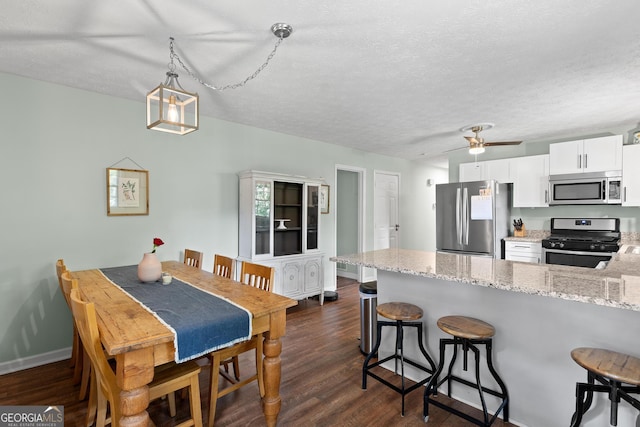 kitchen with a breakfast bar, stainless steel appliances, a peninsula, and dark wood-type flooring